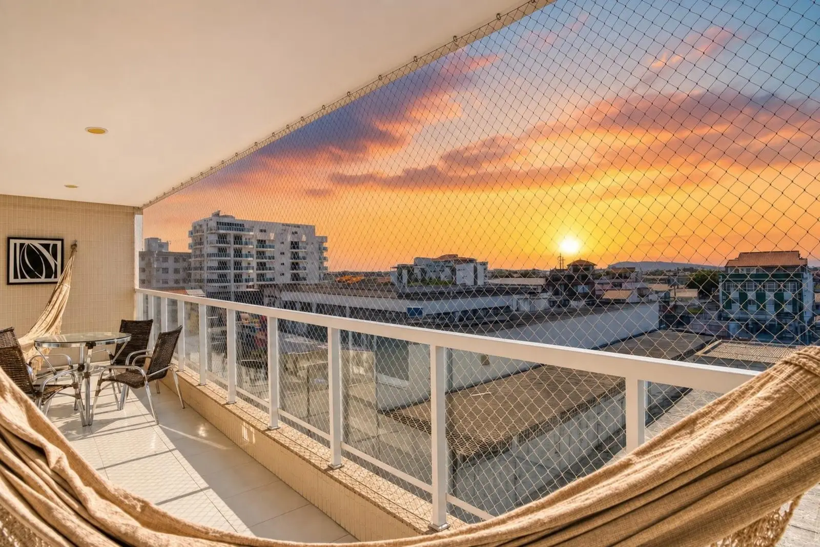 Varanda de imóvel administrado pela RIOS com rede e vista para o pôr do sol em Cabo Frio